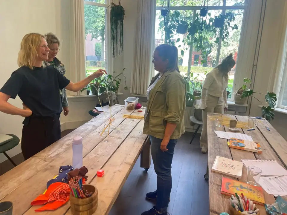 Deelnemers bouwen lachend samen een toren tijdens een actieve opdracht op een praktijkdag